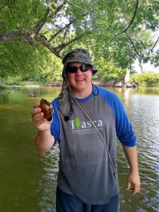 Troy Goodnough standing in the Lac qui Parle River with a Mussel